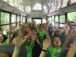 children raising their arms on a bus