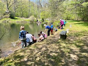 children standing next to a pond