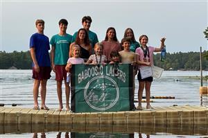 children standing on a dock holding a banner